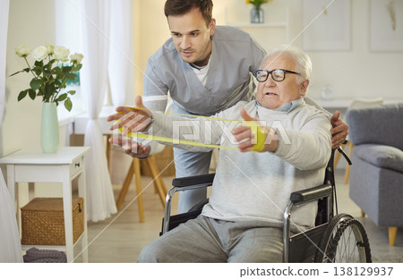 Young therapist helping senior man in wheelchair with exercise to improve mobility and strength. Young therapist helping senior man in wheelchair with exercise to improve mobility and strength. 138129937