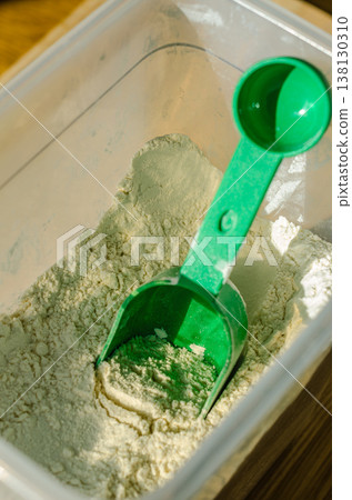 Green scoop in a storage container of baking flour. Close-up on ingredients for home cooking and baking. Green scoop in a storage container of baking flour. Close-up on ingredients for home cooking and baking. 138130310