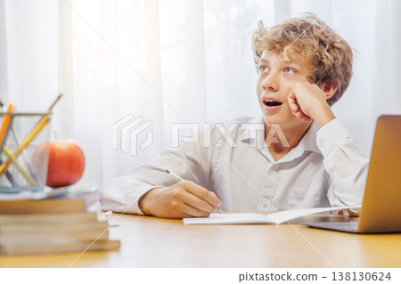 Schoolboy studying at home, doing homework 138130624