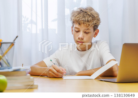 Schoolboy sitting at home, with focus and concentration while doing homework Schoolboy sitting at home, with focus and concentration while doing homework 138130649