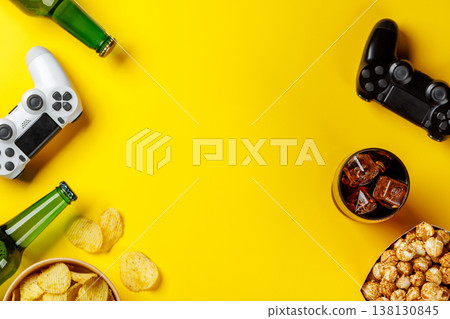Popcorn, potato chips, beer and gamepad on yellow background Popcorn, potato chips, beer and gamepad on yellow background 138130845