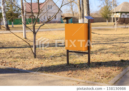 Yellow metal trash bin in a city park. Modern municipal waste container Yellow metal trash bin in a city park. Modern municipal waste container 138130986