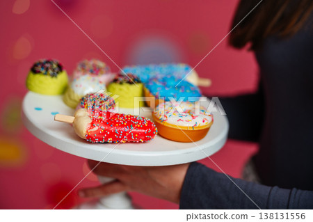 Hand Holding Plate Of Sprinkled Donuts, Cropped Torso And Arm Visible Wearing Dark Sleeve, Warm 138131556