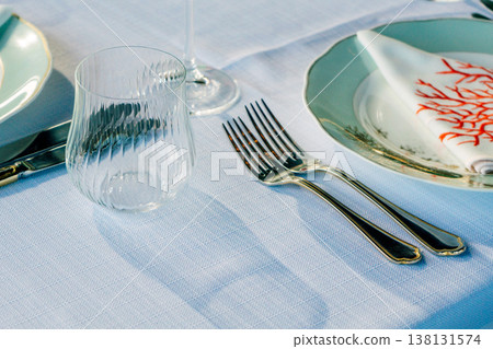 Glassware And Silver Cutlery Arranged On Linen, Coralpatterned Plate Catching Soft Sunlight, Subtle Glassware And Silver Cutlery Arranged On Linen, Coralpatterned Plate Catching Soft Sunlight, Subtle 138131574
