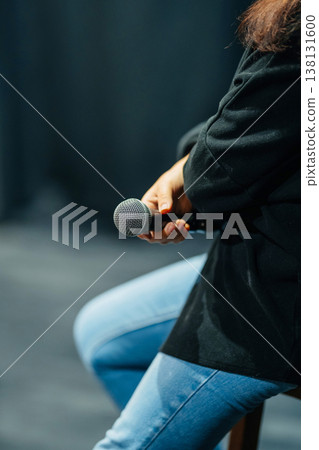 Seated Performer With Microphone And Stool, Preparing For Intimate Stage Moment, Wearing Dark Jacket Seated Performer With Microphone And Stool, Preparing For Intimate Stage Moment, Wearing Dark Jacket 138131600