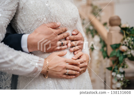 Closeup Hands Of Newlyweds Embracing With Rings And Beaded Gown, Soft Light, Floral Staircase Decor Closeup Hands Of Newlyweds Embracing With Rings And Beaded Gown, Soft Light, Floral Staircase Decor 138131608