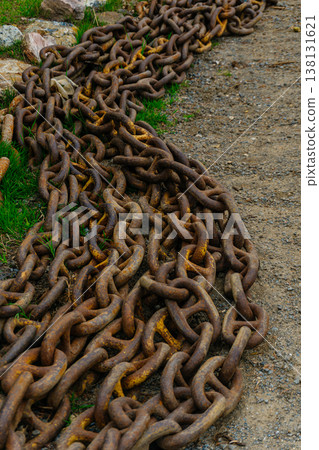 Rusty Anchor Chains Piled Along Weathered Dock, Heavy Links Curving Into Distance, Gritty Gravel . 138131621