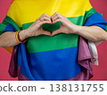 Woman making heart sign while wearing rainbow flag.  138131755