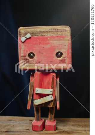 A solo portrait of a handcrafted wooden robot mother with a distressed red finish, featuring a white bow on her head and minimalist metal eyes. 138131766