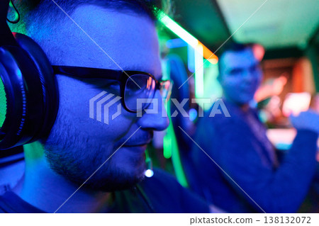 Focused Gamer Wearing Headset With Friend In Neon Gaming Lounge During Team Play Focused Gamer Wearing Headset With Friend In Neon Gaming Lounge During Team Play 138132072