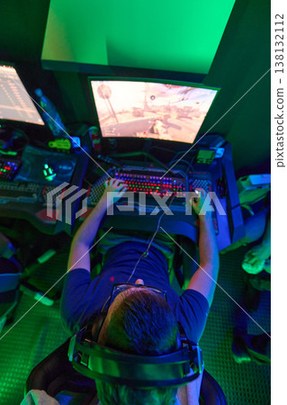Competitive Gamer Playing First-Person Shooter With Headset and RGB Keyboard at Gaming Station Competitive Gamer Playing First-Person Shooter With Headset and RGB Keyboard at Gaming Station 138132112