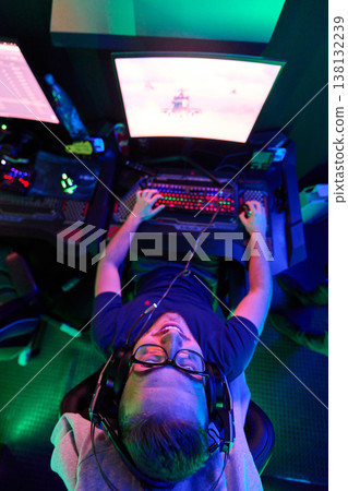 Overhead View Of Gamer Playing PC Video Game With Headset In Neon RGB Gaming Room Overhead View Of Gamer Playing PC Video Game With Headset In Neon RGB Gaming Room 138132239