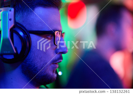 Concentrated Gamer Wearing Headset And Microphone Streaming In Neon-Lit Gaming Room 138132261
