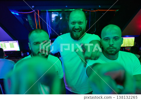 Three Friends Pointing and Cheering in Neon-Lit Gaming Lounge With Excited Men Team Three Friends Pointing and Cheering in Neon-Lit Gaming Lounge With Excited Men Team 138132265