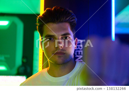 Young Man Portrait in Neon Gaming Arena With Colorful Lights and Focused Expression Young Man Portrait in Neon Gaming Arena With Colorful Lights and Focused Expression 138132266