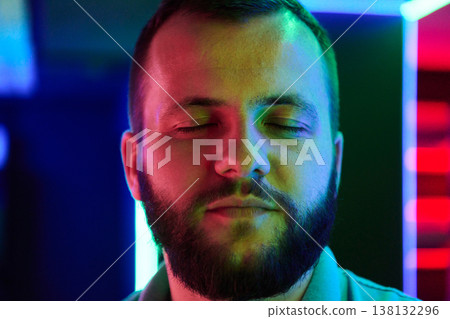 Relaxed Bearded Man Portrait With Closed Eyes Bathed in Colorful Neon Lights in Nightclub 138132296