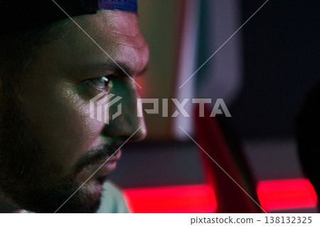 Focused Young Man Profile Portrait With Neon Lighting Concentrating in Low Light Environment Focused Young Man Profile Portrait With Neon Lighting Concentrating in Low Light Environment 138132325