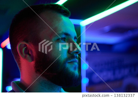 Portrait of Young Bearded Man in Neon Light Looking Thoughtful in Night Tech Environment Portrait of Young Bearded Man in Neon Light Looking Thoughtful in Night Tech Environment 138132337