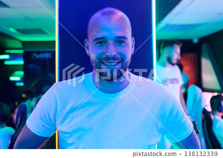 Smiling Competitive Gamer Portrait in Neon Esports Lounge With Teammates and Gaming Setup Smiling Competitive Gamer Portrait in Neon Esports Lounge With Teammates and Gaming Setup 138132339