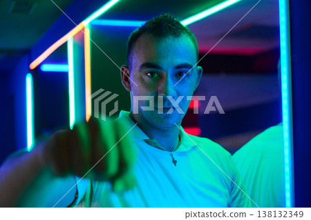 Neon Portrait Of Young Man Reaching Forward In Colorful Club Lighting Neon Portrait Of Young Man Reaching Forward In Colorful Club Lighting 138132349