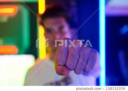 Young Man Pointing Fist Toward Camera With Neon Lights Urban Portrait Gesture Young Man Pointing Fist Toward Camera With Neon Lights Urban Portrait Gesture 138132359