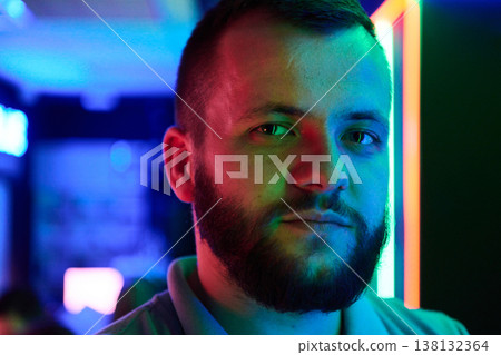 Neon Portrait Of Bearded Man In Colorful Nightclub Lighting With Moody Expression Neon Portrait Of Bearded Man In Colorful Nightclub Lighting With Moody Expression 138132364