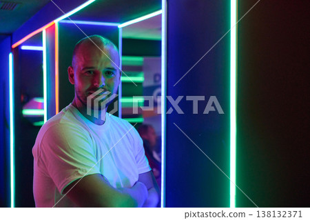 Confident Man Portrait in Neon Lights at Nightclub With Arms Crossed and Casual White T Shirt Confident Man Portrait in Neon Lights at Nightclub With Arms Crossed and Casual White T Shirt 138132371