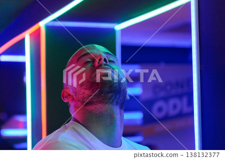 Contemplative Young Man Relaxing Under Neon Lights In Vibrant Nightclub Portrait With Colorful Glow Contemplative Young Man Relaxing Under Neon Lights In Vibrant Nightclub Portrait With Colorful Glow 138132377