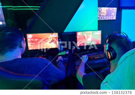 Two Gamers Playing PC Shooter Games With Headsets in Neon Esports Gaming Setup and Teamwork Two Gamers Playing PC Shooter Games With Headsets in Neon Esports Gaming Setup and Teamwork 138132378