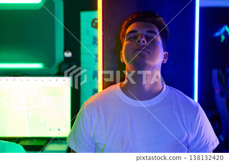 Relaxed Gamer Man With Eyes Closed in Neon-Lit Gaming Room During Late Night Play 138132420