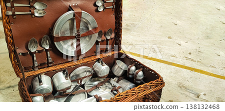 A vintage picnic suitcase with neatly arranged metal plates, cups, and cutlery. It encompasses concepts of retro lifestyle, outdoor recreation, eco-friendliness, and nostalgic travel. A vintage picnic suitcase with neatly arranged metal plates, cups, and cutlery. It encompasses concepts of retro lifestyle, outdoor recreation, eco-friendliness, and nostalgic travel. 138132468