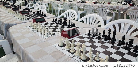 Several chessboards with pieces and digital clocks set up for a tournament in a large hall. Concepts of strategy, competition, intellectual games, and organized events. Several chessboards with pieces and digital clocks set up for a tournament in a large hall. Concepts of strategy, competition, intellectual games, and organized events. 138132470