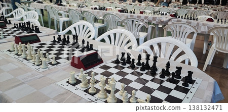 Several chessboards with pieces and digital clocks set up for a tournament in a large hall. Concepts of strategy, competition, intellectual games, and organized events. 138132471