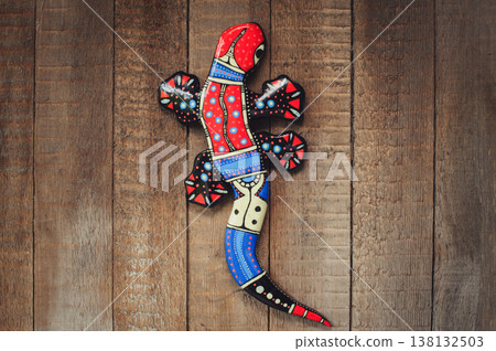 close-up of a handcrafted wooden gecko lizard sculpture, featuring vibrant folk art painting on a rustic wooden background. close-up of a handcrafted wooden gecko lizard sculpture, featuring vibrant folk art painting on a rustic wooden background. 138132503