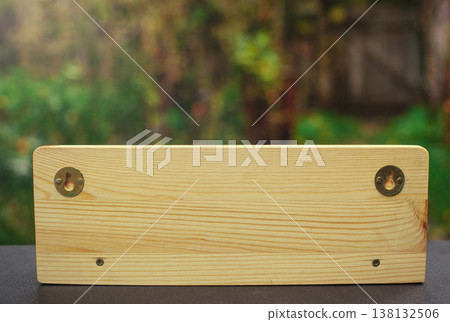 A horizontal back view of a handcrafted wooden wall-mounted key holder, showing metal hanging brackets and grain texture. A horizontal back view of a handcrafted wooden wall-mounted key holder, showing metal hanging brackets and grain texture. 138132506