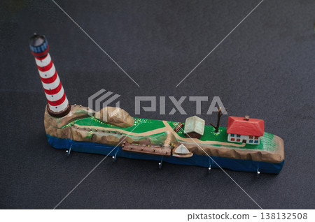 Horizontal top view of a handcrafted wooden key holder with a detailed miniature diorama of a lighthouse on a rocky coast. Horizontal top view of a handcrafted wooden key holder with a detailed miniature diorama of a lighthouse on a rocky coast. 138132508