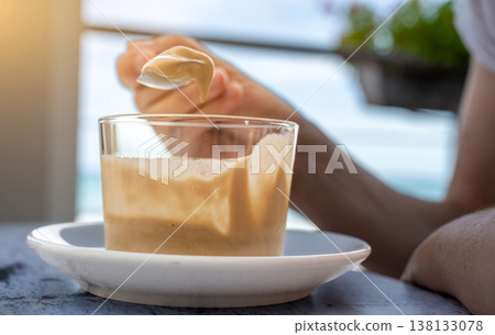 Person savoring creamy coffee mousse with a spoon at an outdoor cafe table, enjoying a refreshing sweet treat in bright daylight relaxed summer indulgence and leisure moment Person savoring creamy coffee mousse with a spoon at an outdoor cafe table, enjoying a refreshing sweet treat in bright daylight relaxed summer indulgence and leisure moment 138133078