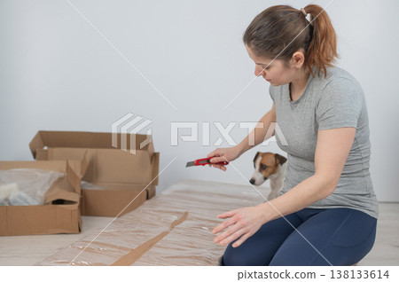A Caucasian woman unpacks a box of furniture. A Caucasian woman unpacks a box of furniture. 138133614
