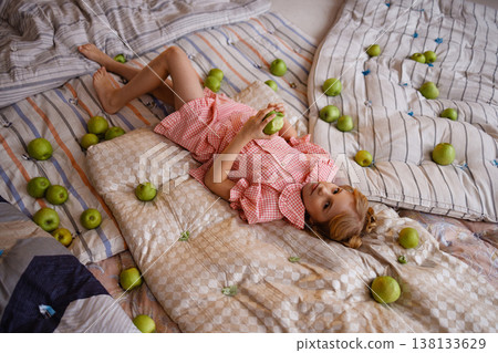 Little girl lying on mattresses with green apples, top view, princess and the pea concept 138133629