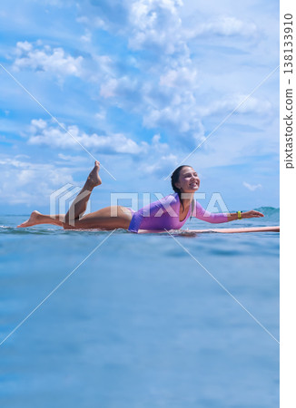 Serene Surfer Dressed In Pink Diligently Paddling Through Relaxing Ocean Waves Serene Surfer Dressed In Pink Diligently Paddling Through Relaxing Ocean Waves 138133910