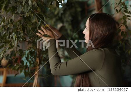 Person meticulously trimming and nurturing houseplant under warm lighting Person meticulously trimming and nurturing houseplant under warm lighting 138134037