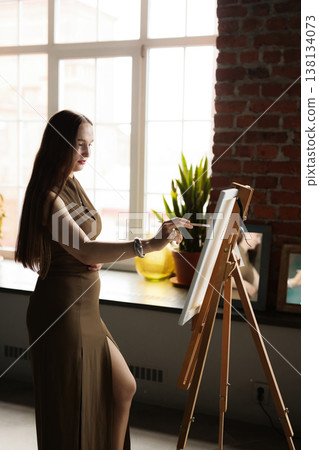 Woman painter working attentively in cozy creative setting 138134073
