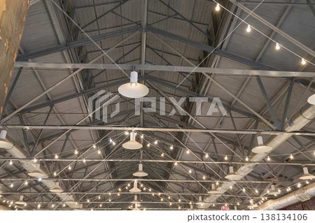 Spacious Industrial Setting. Open Industrial Venue Illuminated By String Lights And Exposed Structures 138134106