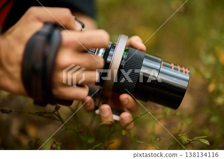 Amateur photographer carefully adjusting lens amidst nature scene Amateur photographer carefully adjusting lens amidst nature scene 138134116