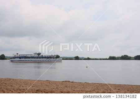 Peaceful boat on calm waters near sandy shoreline under cloudy sky 138134182