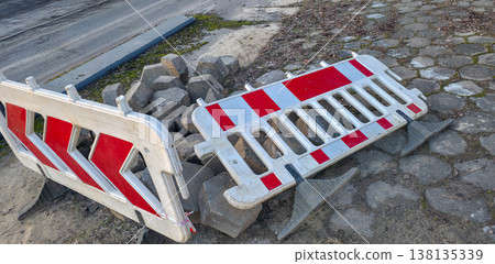 Road paving slabs piled up and cordoned off with warning signs. Road construction and repair in urban conditions. High quality photo 138135339