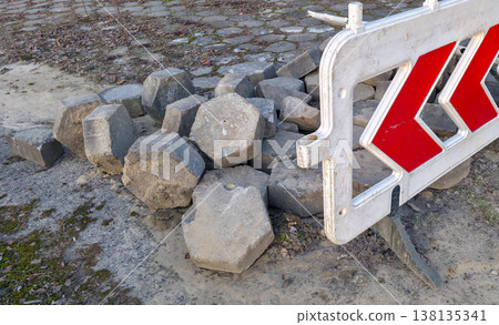 Road paving slabs piled up and cordoned off with warning signs. Road construction and repair in urban conditions. High quality photo 138135341