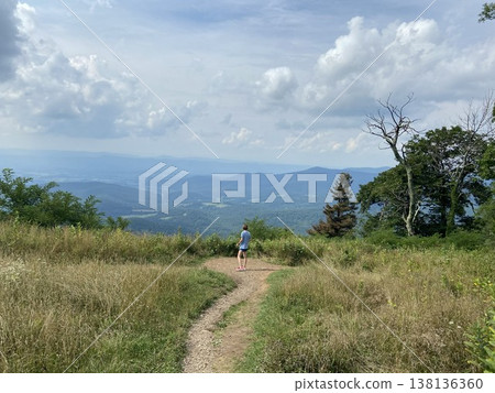 A woman stands on a hiking trail overlooking the Blue Ridge Mountains on Skyline Drive in Virginia. 138136360