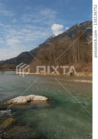 Clear Alpine River with Foreground Rock and Mountain Slope 138136752