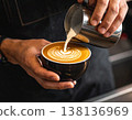 A skilled barista carefully pours steamed milk into a dark ceramic cup 138136969